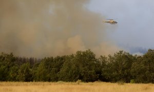 Un helicóptero trabaja en el incendio de Monsagro que los vientos cambiantes y el fuerte calor mantienen activo y dificultan su estabilización, este viernes en Salamanca.