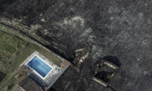 Fotografía tomada con un dron de una piscina y una construcción rodeadas por la superficie calcinada en el pueblo de San Cibrao, Oímbra, Ourense.