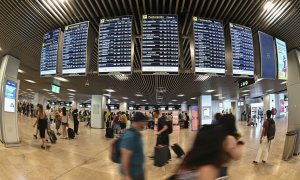 Varios pasajeros pasan por las pantallas de información en el aeropuerto Adolfo Suárez Madrid-Barajas, a 25 de julio de 2022.