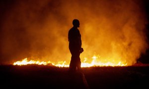 Un vecino ante las llamas mientras colabora en las labores de extinción del incendio de Cures, en Boiro, A Coruña.
