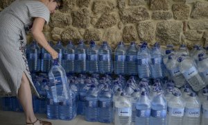 08/08/2022 Una mujer coge una botella de agua embotellada en el local que el Gobierno local de Ribadavia ha habilitado para que se abastezcan los vecinos más afectados por los cortes de suministro, a 7 de agosto de 2022