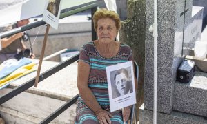 Benita Navacerrada sostiene un cartel con la foto de su padre junto a la fosa común del cementerio parroquial de Colmenar Viejo (Madrid), donde fue enterrado con decenas de republicanos fusilados en 1939.