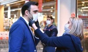 Mujer poniendo ayudando a poner una mascarilla en Austria a principios de la pandemia-01/04/2020