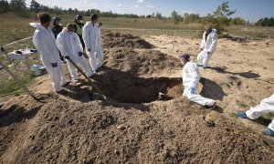 Técnicos forenses trabajan en un lugar de entierro cerca de la ciudad recientemente recuperada de Lyman, en la región de Donetsk.