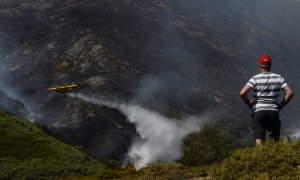 26/08/2022-Un vecino de Senderiz en Lobeira observa un hidroavión trabajar en el incendio forestal en la Serra do Leboreiro, sobrevuela una explotación ganadera, en el parque natural de Baixa Limia e Serra do Xurés, a 26 de agosto de 2022, en Serra do Xur