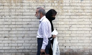 Dos personas, una de ellas una mujer sin velo, pasean por la calle de Teherán.