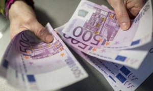 Una persona sostiene varios billetes de 500 euros
