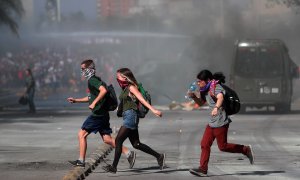Los manifestantes corren después de que los tanques de las fuerzas de seguridad arrojen gases lacrimógenos hacia los manifestantes durante los enfrentamientos, luego de una protesta contra el gobierno.