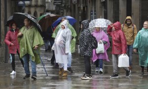 Turistas y peregrinos se protegen de la lluvia en Santiago de Compostela, este jueves.