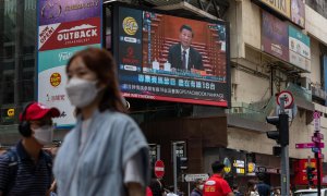 Ciudadanos caminan por una céntrica calle de Hong Kong junto a una pantalla gigante con el presidente de China, Xi Jinping, durante su intervención en el Congreso Nacional del Partido Comunista de China el 22 de octubre de 2022.