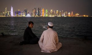13/11/2022 Dos hombres charlan a la orilla del río con vistas al 'skyline' de Doha (Qatar)