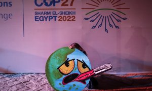 Una activista sujeta una pancarta con la imagen de la  imagen de la tierra entrando en ebullición por la crisis climática en la Cumbre del Clima de Sharm el Sheikh (COP27).