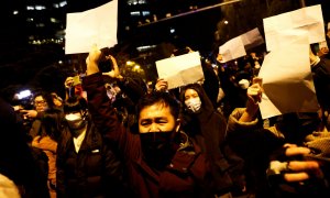 Manifestantes se concentran y sostienen hojas de papel blancas en protesta por las restricciones 'covid zero', mientras homenajean a las víctimas de un incendio en Urumqi (China)