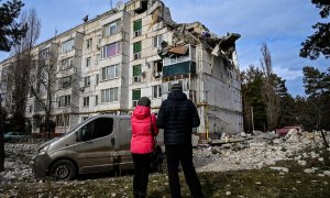 02/12/2022 Dos personas residentes en la zona observan los daños en un bloque de viviendas bombardeado en la ciudad ucraniana de Kluhyno-Bashkyrivka (Járkov)