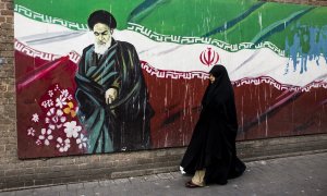 Una mujer junto a un mural con la bandera iraní y el ayatolá Ruholá Jomeini en Teherán (Irán). Imagen de Archivo.