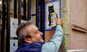 Una persona pone el décimo recién comprado en el azulejo que representa a el gato negro en la administración de loterías ‘El Gato Negro’ en Sevilla- 07/12/2022