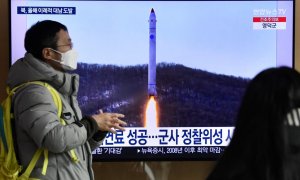 Un hombre frente a una televisión que muestra una transmisión de noticias con imágenes de archivo de una prueba de misiles de Corea del Norte el 31 de diciembre de 2022.