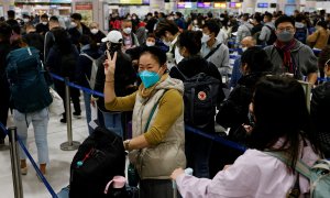 Una mujer celebra en una abarrotada estación de Lok Ma Chau, en Hong Kong, la reapertura de fronteras en China