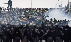 Los policías observan a los miles de seguidores ultras de Bolsonaro que han asaltado el Congreso de Brasil.