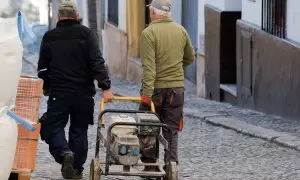 Dos trabajadores trasladan un generador eléctrico por una calle de la localidad malagueña de Ronda. REUTERS/Jon Nazca