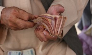 Un hombre cuenta efectivo en un mercado de cambio de dinero en Kabul, Afganistán