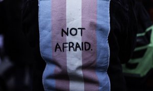 Imagen de archivo de una persona con un chaleco con una bandera trans en la espalda con las palabras "Sin miedo"