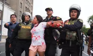 Policías antidisturbios arrestan a una mujer luego de arrojar pintura roja a policías cuando cientos marchan por la paz en Lima y las principales ciudades del país luego de los disturbios de diciembre pasado contra el actual gobierno de Dina Boluarte y el
