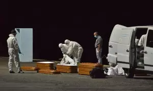 Varios trabajadores introducen en un ataúd a una persona fallecida en alta mar tras intentar llegar a la costa a bordo de una patera, a 11 de abril de 2021, en el puerto de la Restinga, Canarias.
