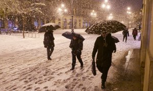 Varias personas caminan por una calle nevada, a 19 de enero de 2023, en Pamplona, Navarra.