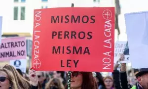 Una mujer porta una pancarta con el lema 'Mismos perros, misma ley' durante una manifestación contra la caza en Madrid.
