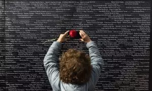 Una mujer hace una foto del nombre de su familiar, colocado en un panel junto a los nombres de las demás víctimas, durante el acto "institucional" de cierre de la fosa de Pico Reja. A 21 de febrero de 2023, en Sevilla (Andalucía, España).
