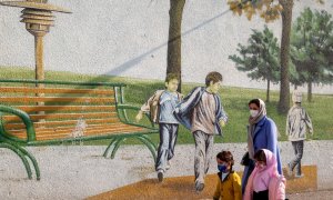 Una mujer pasea junto a sus hijos frente a un mural infantil en Teherán.