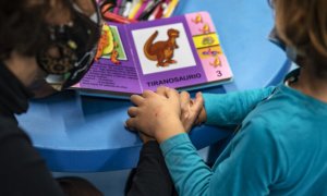 Dos niños en una guardería mirando un libro infantil.