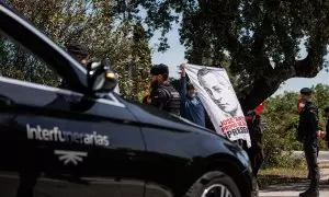 El coche fúnebre con los restos de José Antonio Primo de Rivera, salen de la basílica del Valle de Cuelgamuros, mientras simpatizantes de la falange sujetan una tela con su rostro, a 24 de abril de 2023, en San Lorenzo de El Escorial, Madrid