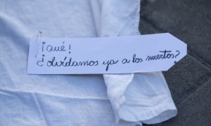 Un letrero que reza '¡Qué! ¿Olvidamos ya a los muertos?' en una ‘performance’, de Marea de Residencias y Verdad y Justicia, para protestar por los fallecimientos de mayores durante la pandemia, en las puertas de la Asamblea de Madrid, a 2 de marzo de 2023