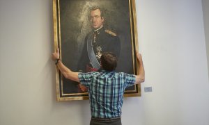 Un operario retira el retrato del rey emérito Juan Carlos I en la Sala de Gobierno del Parlamento de Navarra