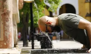 Un hombre se refresca la cabeza en una fuente del Patio de los Naranjos de la Mezquita-Catedral de Córdoba.