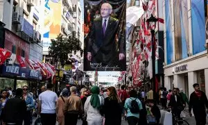 Gente en una calle de Izmir camina debajo de un poster de Kemal Kiliçdaroglu.