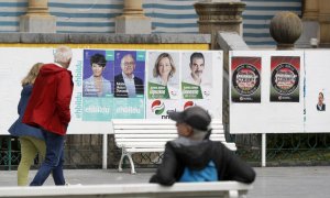 Unos ciudadanos observan varios carteles electorales este martes en San Sebastián, a 16 de mayo de 2023.
