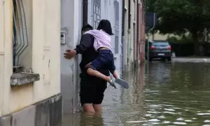 Un hombre y una niña abandonan su vivienda tras las fuertes inundaciones en la región de Emilia Romaña, en el noreste de Italia.