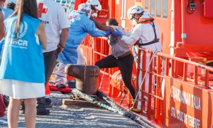 Agentes de salvamento marítimo ayudan a una mujer migrante a desembarcar de la guardamar Talía en Arguineguín.