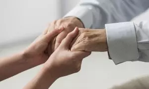 Una enfermera sostiene las manos de una persona mayor