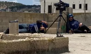 Periodistas palestinos se ponen a cubierto mientras son atrapados bajo fuego en un techo mientras cubrían una redada israelí en Jenin, en Cisjordania ocupada por Israel, el 19 de junio de 2023.