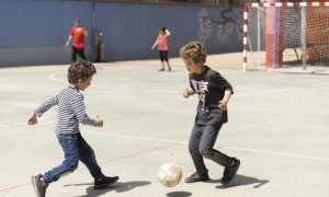 Dos niños jugando a pelota en el patio de un centro escolar de Barcelona.