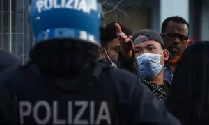 Un manifestante hace gestos hacia un oficial de policía mientras los migrantes protestan en el centro de recepción de migrantes de Torre Maura, donde están en cuarentena debido a posibles infecciones por coronavirus, 14 de abril de 2020, en Roma (Italia).