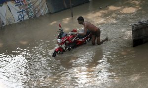 13/07/2023.- Un hombre empuja su moto en una zona inundada cerca del río Yamuna en Nueva Delhi, India, 13 de julio de 2023.