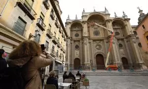 Varios operarios, subido a una grúa , revisan la fachada de la Catedral de Granada. Archivo.