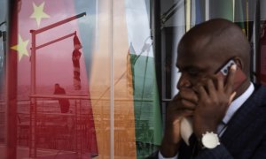 Un hombre habla por su teléfono móvil mientras pasa por una ventana en la que se reflejan las banderas de los BRICS, a 2 de junio de 2023 en Cape Town