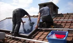 Dos instaladores colocan placas solares en el edificio de una vivienda, en una imagen de archivo