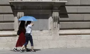 06/08/2023.- Dos mujeres se protegen del sol en Madrid este domingo .
